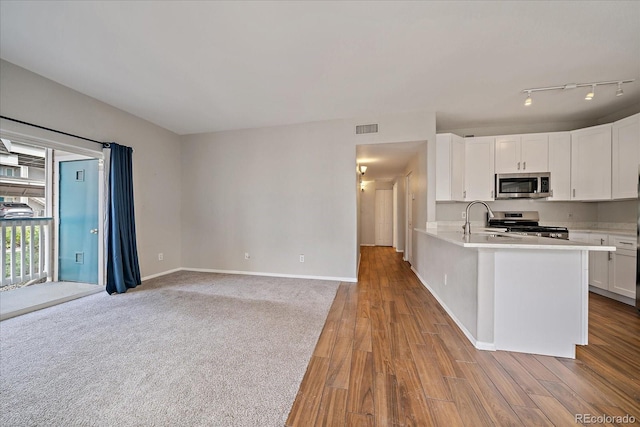 kitchen with stainless steel appliances, light countertops, white cabinetry, a sink, and baseboards