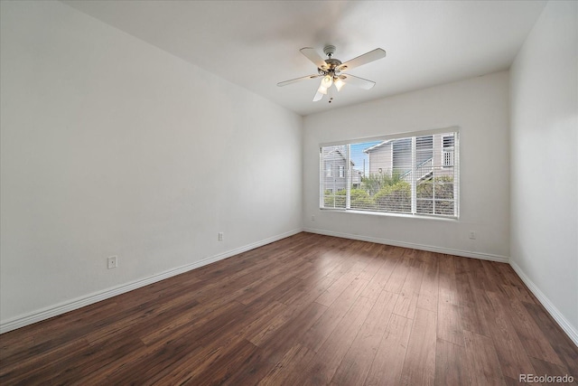 empty room featuring dark wood finished floors, baseboards, and ceiling fan