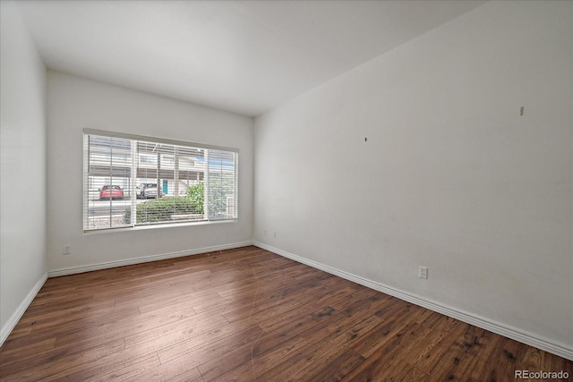 unfurnished room with dark wood-type flooring and baseboards