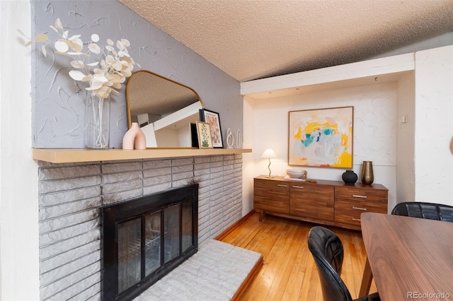 sitting room featuring lofted ceiling, a fireplace, hardwood / wood-style floors, and a textured ceiling