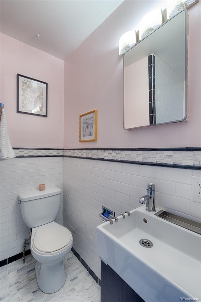 bathroom featuring vanity, toilet, and tile walls