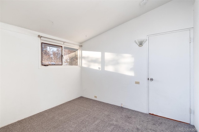 carpeted empty room with vaulted ceiling