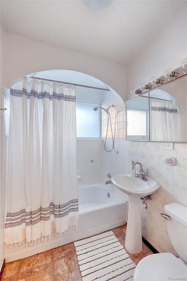 bathroom with tile walls, shower / tub combo with curtain, and toilet