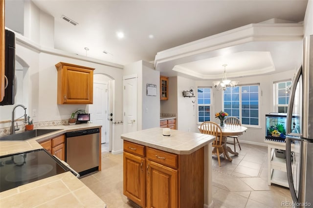 kitchen with visible vents, a sink, a tray ceiling, stainless steel appliances, and tile counters