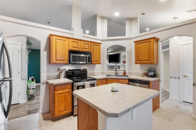 kitchen with visible vents, tile countertops, appliances with stainless steel finishes, arched walkways, and a sink