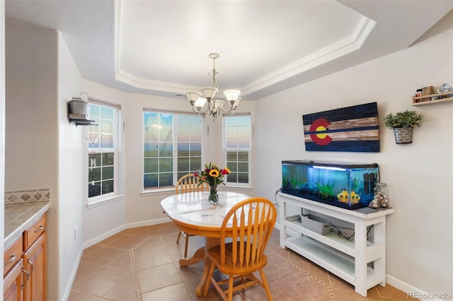 dining area with light tile patterned floors, baseboards, a raised ceiling, and an inviting chandelier