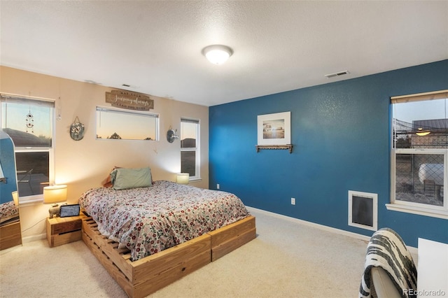 carpeted bedroom with visible vents, a textured ceiling, and baseboards