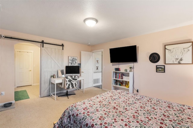 carpeted bedroom featuring visible vents, baseboards, and a barn door