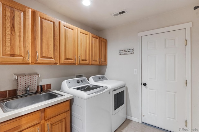 washroom featuring light tile patterned floors, visible vents, cabinet space, a sink, and washing machine and dryer