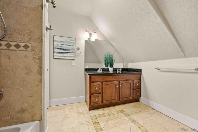 bathroom with tile patterned flooring, vaulted ceiling, and vanity