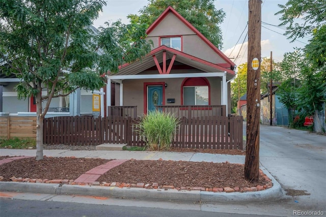 view of front of property featuring stucco siding, a porch, and a fenced front yard