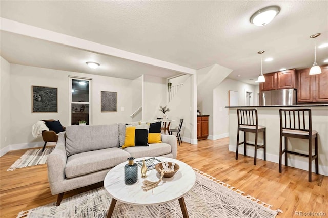 living area with baseboards, light wood finished floors, and a textured ceiling