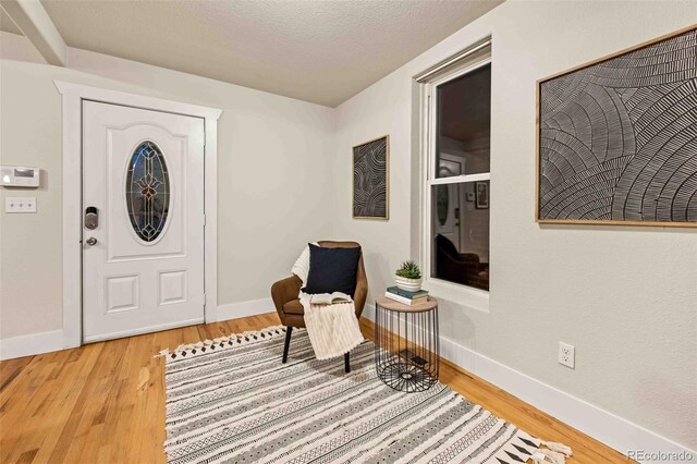 foyer featuring a textured ceiling, baseboards, and wood finished floors