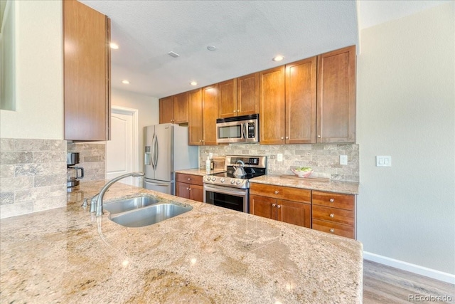 31112 Black Eagle Dr Unit 101, Evergreen, CO 80439 - kitchen featuring appliances with stainless steel finishes, light stone counters, brown cabinetry, backsplash, and recessed lighting