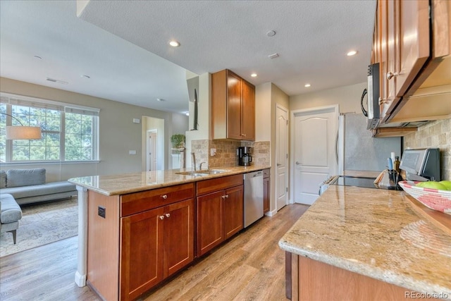 31112 Black Eagle Dr Unit 101, Evergreen, CO 80439 - kitchen with stainless steel appliances, light wood-type flooring, decorative backsplash, light stone countertops, and a peninsula