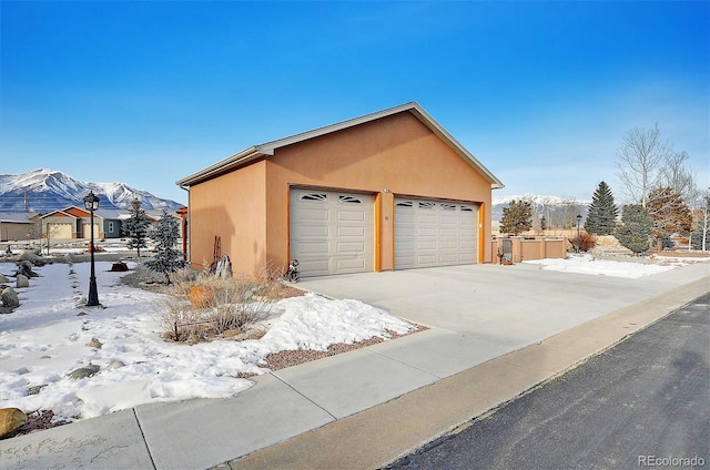 view of snow covered exterior featuring a mountain view, a garage, and an outdoor structure