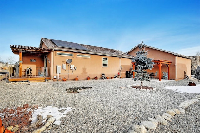 rear view of property with a pergola and solar panels