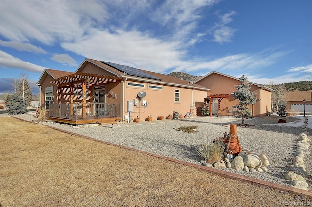 back of property featuring a pergola and solar panels