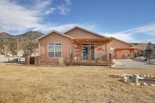 back of property with a pergola, a lawn, and a mountain view