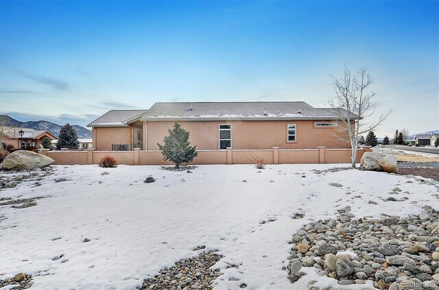 snow covered rear of property featuring a mountain view