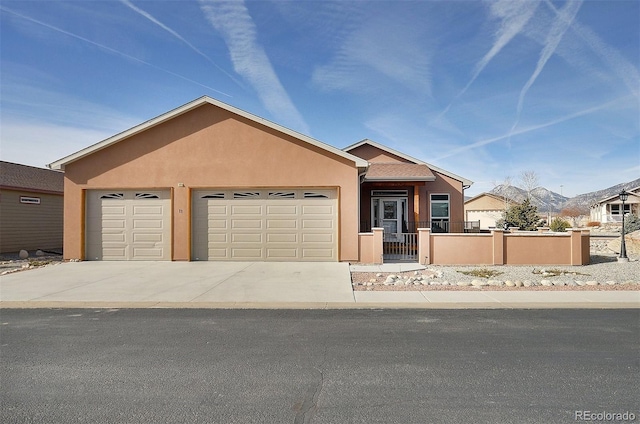 view of front of home featuring stucco siding, a garage, a fenced front yard, and driveway