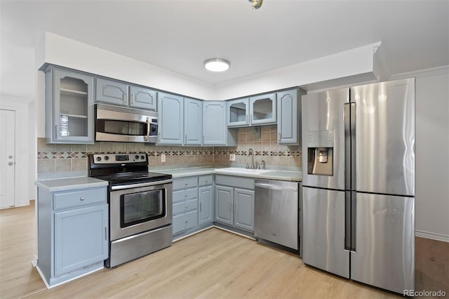 971 S Ironton St, Aurora, CO 80012 - kitchen featuring stainless steel appliances, gray cabinetry, light wood finished floors, light countertops, and glass insert cabinets