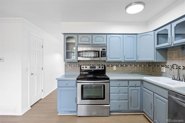 971 S Ironton St, Aurora, CO 80012 - kitchen with appliances with stainless steel finishes, backsplash, light wood-style flooring, light countertops, and glass insert cabinets