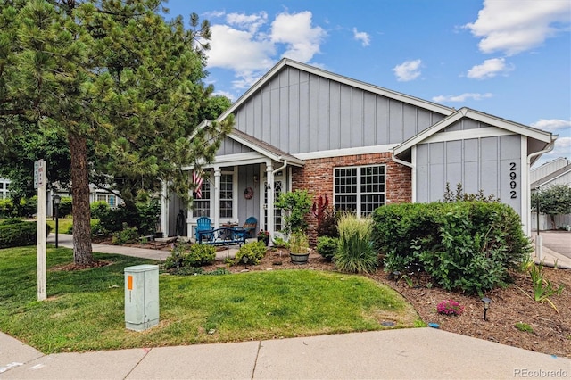 2992 W Long Dr Unit A, Littleton, CO 80120 - view of front of property featuring a front lawn, covered porch, board and batten siding, and brick siding