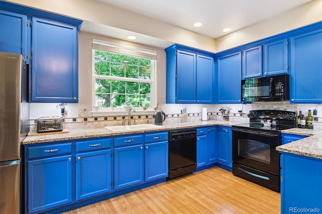2992 W Long Dr Unit A, Littleton, CO 80120 - kitchen with black appliances, blue cabinets, light wood-style floors, light stone counters, and backsplash