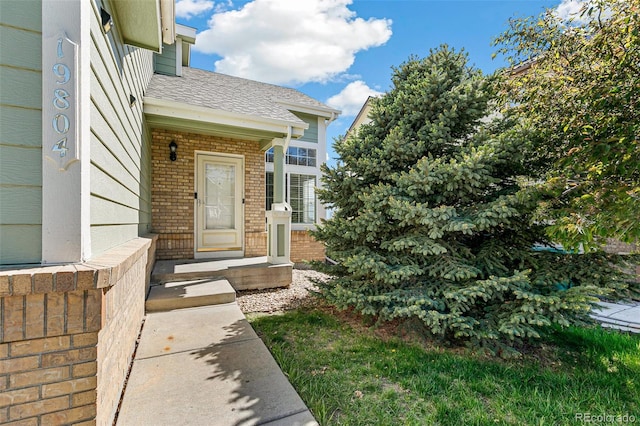 property entrance with brick siding and roof with shingles