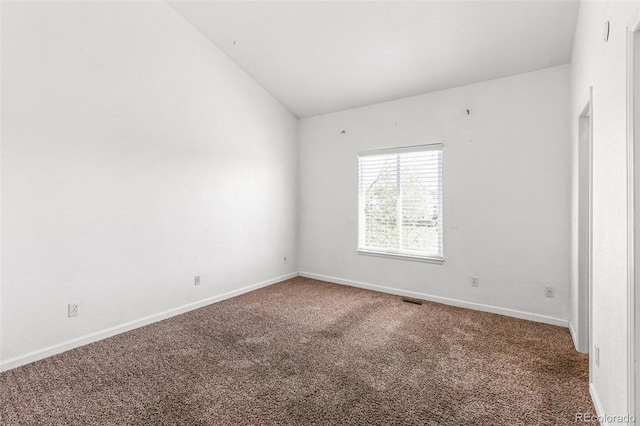 carpeted empty room featuring vaulted ceiling and baseboards