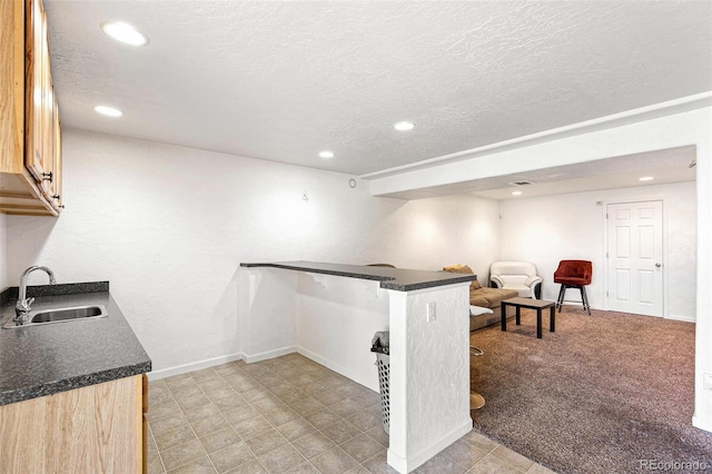 kitchen featuring a sink, recessed lighting, dark countertops, a textured ceiling, and a peninsula