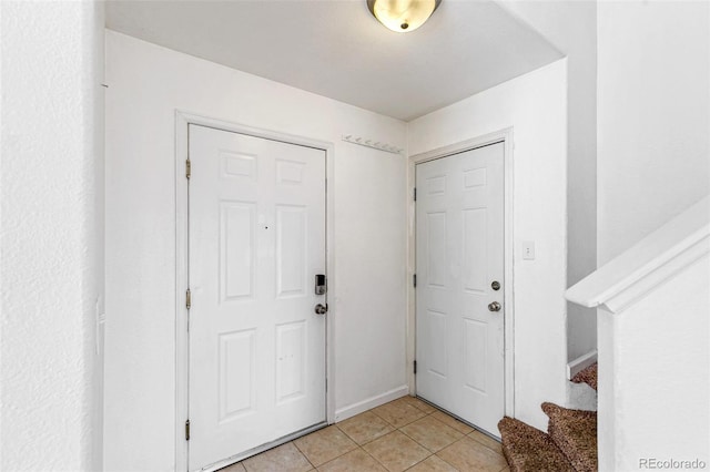 foyer featuring light tile patterned flooring, stairway, and baseboards
