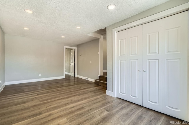 2726 W 1st Ave, Denver, CO 80219 - unfurnished living room featuring a textured ceiling, wood finished floors, recessed lighting, and stairway