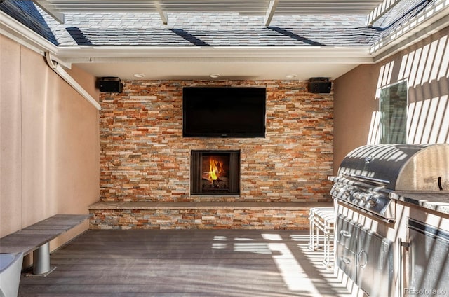 wooden deck with grilling area, a lit fireplace, and an outdoor kitchen