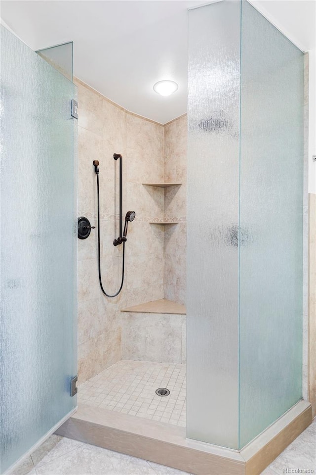 full bath featuring tile patterned flooring and a shower stall