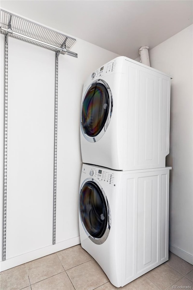 clothes washing area featuring light tile patterned flooring, laundry area, and stacked washing maching and dryer