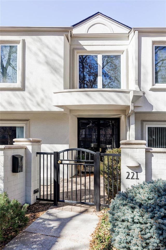 view of exterior entry featuring a gate, fence, and stucco siding