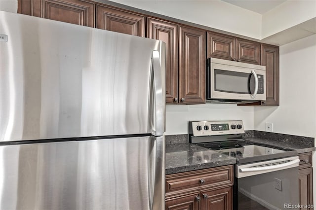 kitchen featuring appliances with stainless steel finishes, dark brown cabinets, and dark stone counters