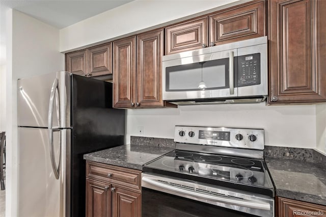 kitchen featuring appliances with stainless steel finishes, dark brown cabinets, and dark stone counters