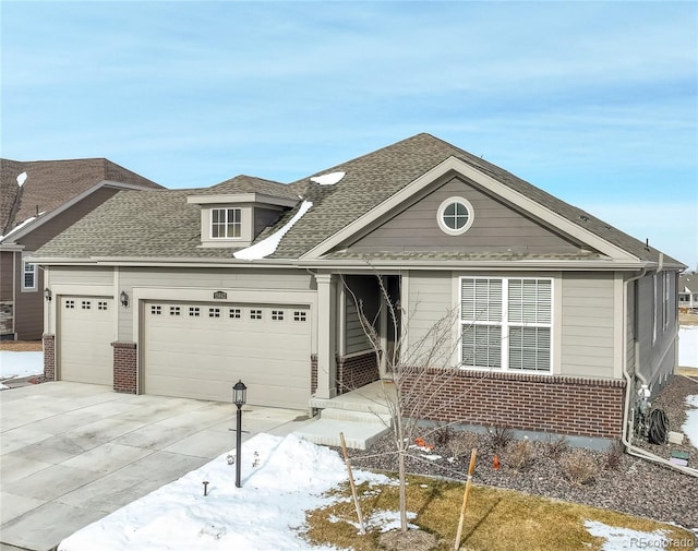 view of front of property featuring a shingled roof, concrete driveway, brick siding, and an attached garage