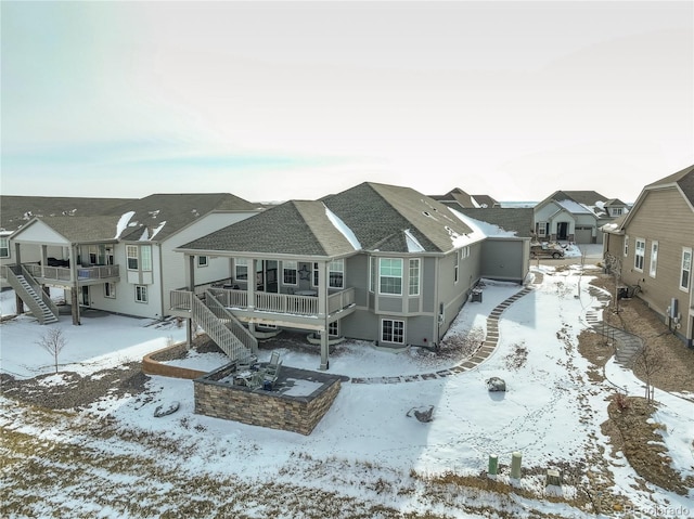 snow covered house with a deck, a residential view, and stairway