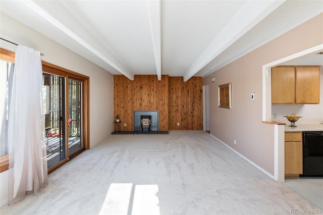 unfurnished living room with light colored carpet, beamed ceiling, a wood stove, wood walls, and baseboards