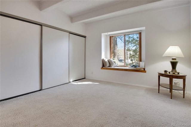 unfurnished bedroom with beam ceiling, carpet floors, and a closet