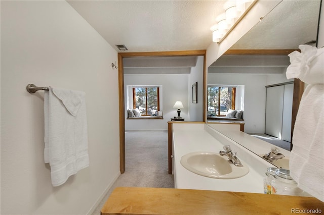 bathroom featuring healthy amount of natural light, baseboards, vanity, and a textured ceiling