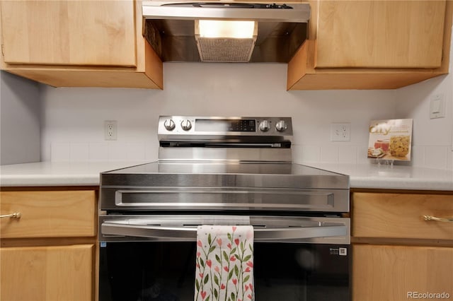 kitchen featuring electric range, wall chimney range hood, light brown cabinets, and light countertops
