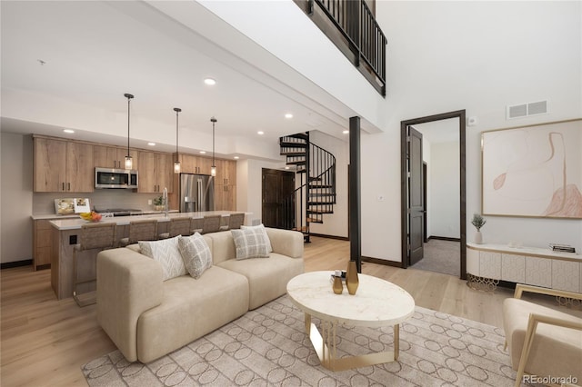 living room with a high ceiling, sink, and light hardwood / wood-style floors