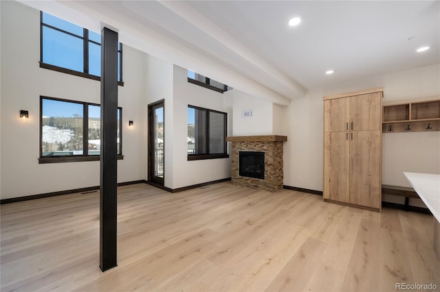 unfurnished living room featuring a stone fireplace and light hardwood / wood-style flooring