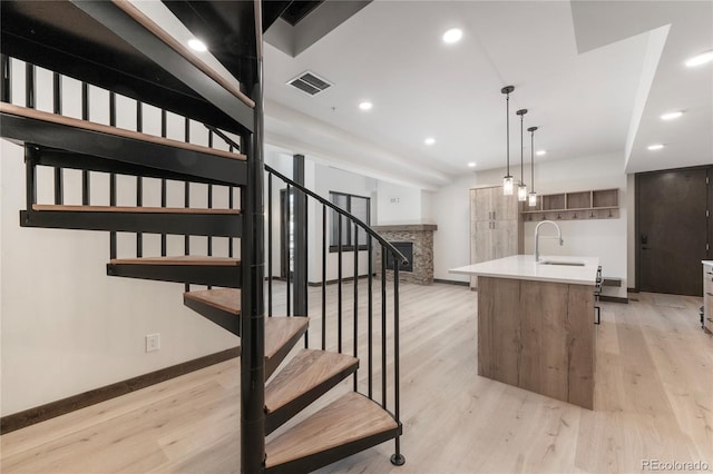 stairway with wood-type flooring, a stone fireplace, and sink