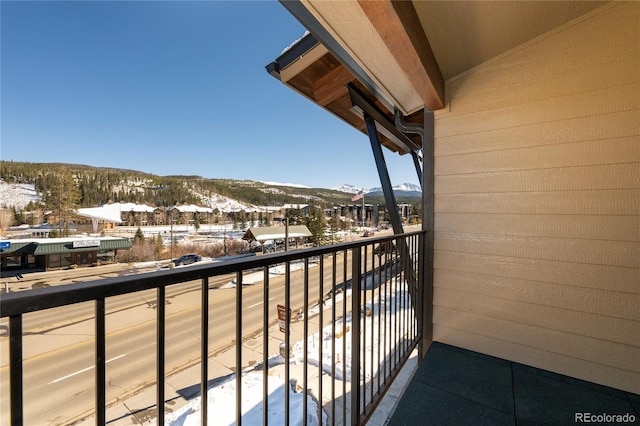 snow covered back of property featuring a mountain view